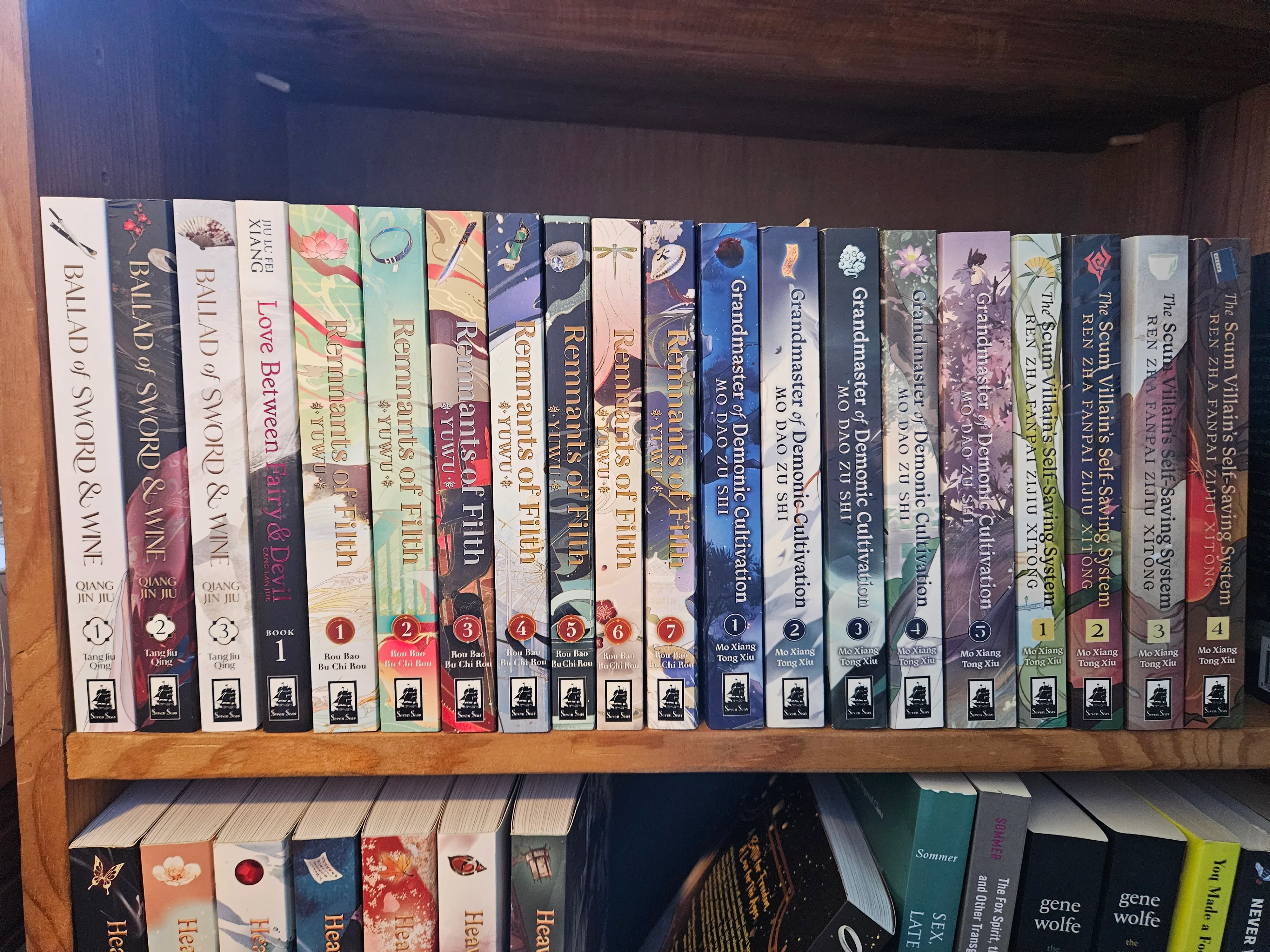 a bookshelf containing a number of Seven Seas danmei volumes. Spines of the newer titles are more simple and readable, with greater attention paid to contrast and visual balance