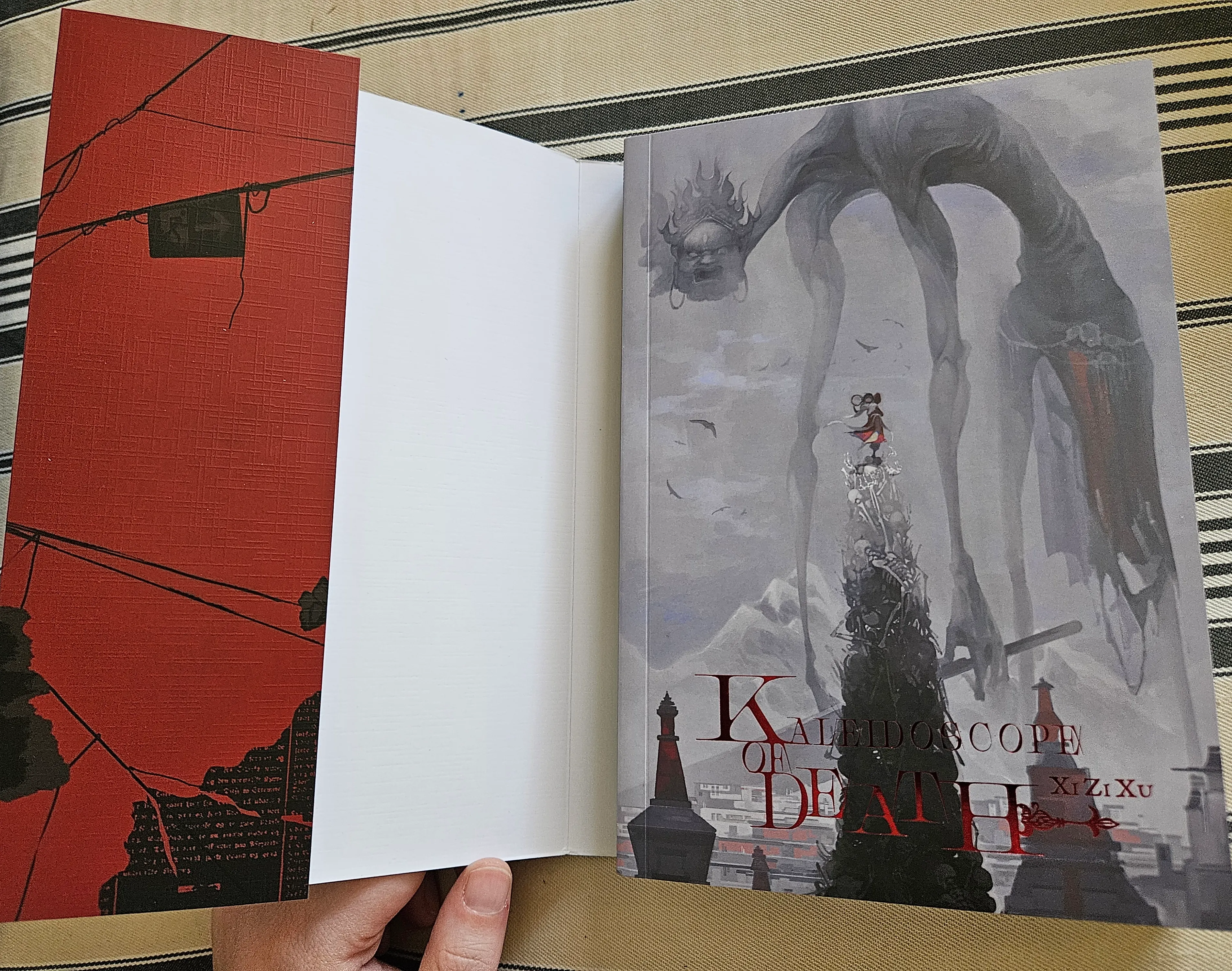 the inner cover of Kaleidoscope of Death, which depicts a person standing on a mountain of skulls as an immense monster looms behind them in the fog